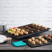 An Elite Global Solutions black faux slate melamine serving board with cookies and macaroons on a table.