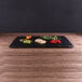 An Elite Global Solutions rectangular faux black slate melamine serving board with vegetables on it.