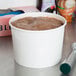 A close up of a white Choice paper frozen yogurt container with chocolate inside.