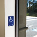 A blue and white Thunder Group handicap accessible sign on a wall.