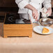 A chef using a Cal-Mil countertop induction cooker to cook food on a table.