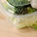 A Dart plastic container with a lid filled with broccoli and cauliflower on a counter.