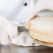 A person in white gloves using a Dexter-Russell clam knife to cut a large clam.