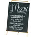 A Cal-Mil brass menu sign holder with white writing on a chalkboard.