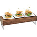 A row of waffle sandwiches on a wooden table with a Cal-Mil walnut wood and chrome reversible riser.