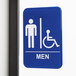 A blue and white sign with a man and wheelchair symbol for a men's restroom.