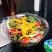 A salad in a Dart plastic container with a drink.