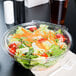 A salad in a Dart plastic container with a white flat lid and a plastic fork.