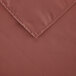 A close-up of a mauve rectangular cloth table cover with a corner