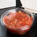 A Dart plastic tamper-evident bowl of salsa on a counter.