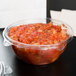A Dart plastic deli bowl filled with salsa on a table.