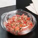 A Dart plastic deli container filled with salsa on a table.