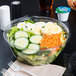 A Dart plastic bowl filled with salad on a counter.