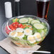 A salad in a Dart plastic bowl with a clear dome lid.