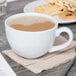A Tuxton porcelain cappuccino cup of coffee on a table with cookies.
