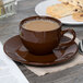 A Tuxton mahogany cappuccino cup on a saucer with cookies.
