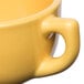 A close-up of a yellow Tuxton jumbo cappuccino cup with a handle.