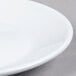A close up of a Tuxton porcelain white saucer with a small hole in the middle.