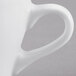 A close-up of a Tuxton white porcelain espresso cup with a handle.