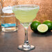 A Libbey margarita glass filled with a drink and a lime half on the rim.