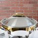 A silver Vollrath Panacea chafer cover with gold trim.
