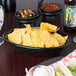 A charcoal oval weave polyethylene basket filled with tortilla chips on a table.