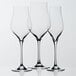 Three Stolzle wine flute glasses on a white surface.