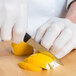 A person in white gloves using a Victorinox spear point paring knife to cut a lemon.