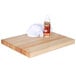 A white towel and bottle of Emmet's Elixir wood conditioner on a wooden cutting board.