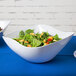 A white GET San Michele flare bowl filled with salad on a table.