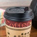 A black Royal Paper Stix To Go beverage plug in a coffee cup with a lid.