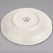 A white Homer Laughlin narrow rim saucer with a small design on it.