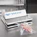 A Vollrath external strip vacuum packaging machine on a counter with a piece of meat in a vacuum bag.
