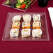 A plate of sushi rolls on a WNA Comet clear square plastic plate on a table.