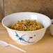 A blue melamine scalloped bowl filled with rice and vegetables with a white spoon.