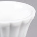 A close up of a CAC Bone White China Floral Ramekin with a rippled edge.