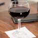 A Libbey Bolla Grande wine glass filled with red wine on a table.