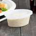 A Pactiv Newspring Ellipso plastic souffle container with white lid containing white sauce.