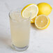A Libbey customizable beverage glass filled with lemonade and a straw with a lemon wedge on the rim.