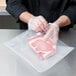 A person wearing gloves using ARY VacMaster Full Mesh Vacuum Packaging Bags to package a piece of meat.