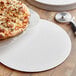 An 18" corrugated white cake circle holding a pizza on a table.