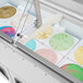 A Turbo Air green low curved glass ice cream dipping cabinet filled with different colored ice cream.