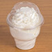 A Fabri-Kal clear plastic dome lid on a plastic cup filled with white whipped cream.