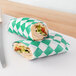 A sandwich wrapped in green and white Choice deli sandwich paper.