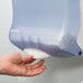 A hand reaching out to a San Jamar Ultrafold paper towel dispenser in Arctic Blue.