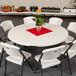 A Lifetime round folding table with white chairs and a potted plant.