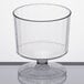A WNA Comet clear plastic wine cup with a round pedestal on a white surface.