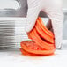 A person in gloves using a Vollrath Tomato Pro slicer to cut a tomato.