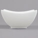 An Arcoroc white porcelain square bowl with curved edges on a gray surface.