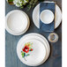 A table set with white Fiesta® luncheon plates with a flower design on them.